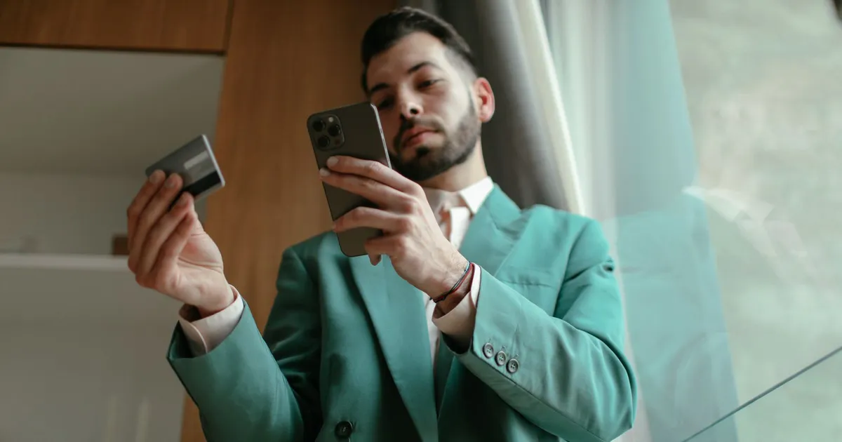 Man checking a CPC SCP charge on his credit card statement on his phone, card in hand