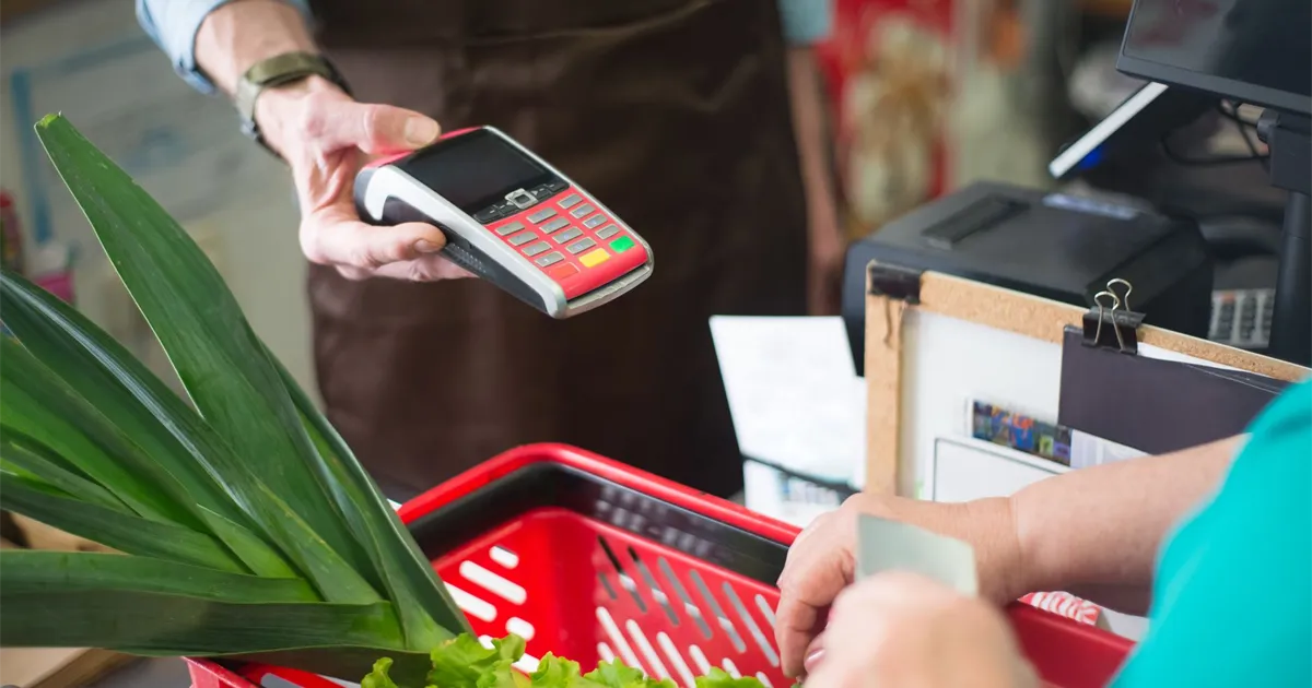 Tapping a cashback credit card at a grocery checkout in Canada