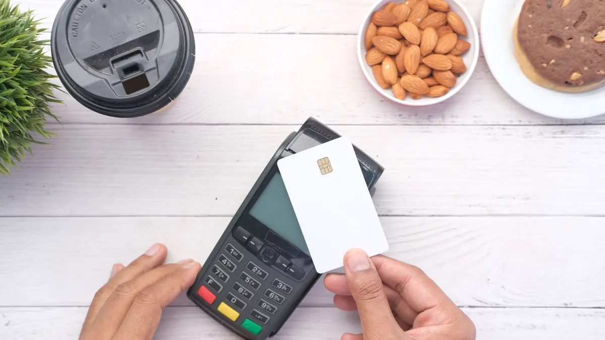Tapping a card on a terminal beside a coffee, the everyday test of the card you choose