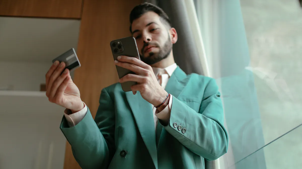 Man checking an application on his phone with his card in hand